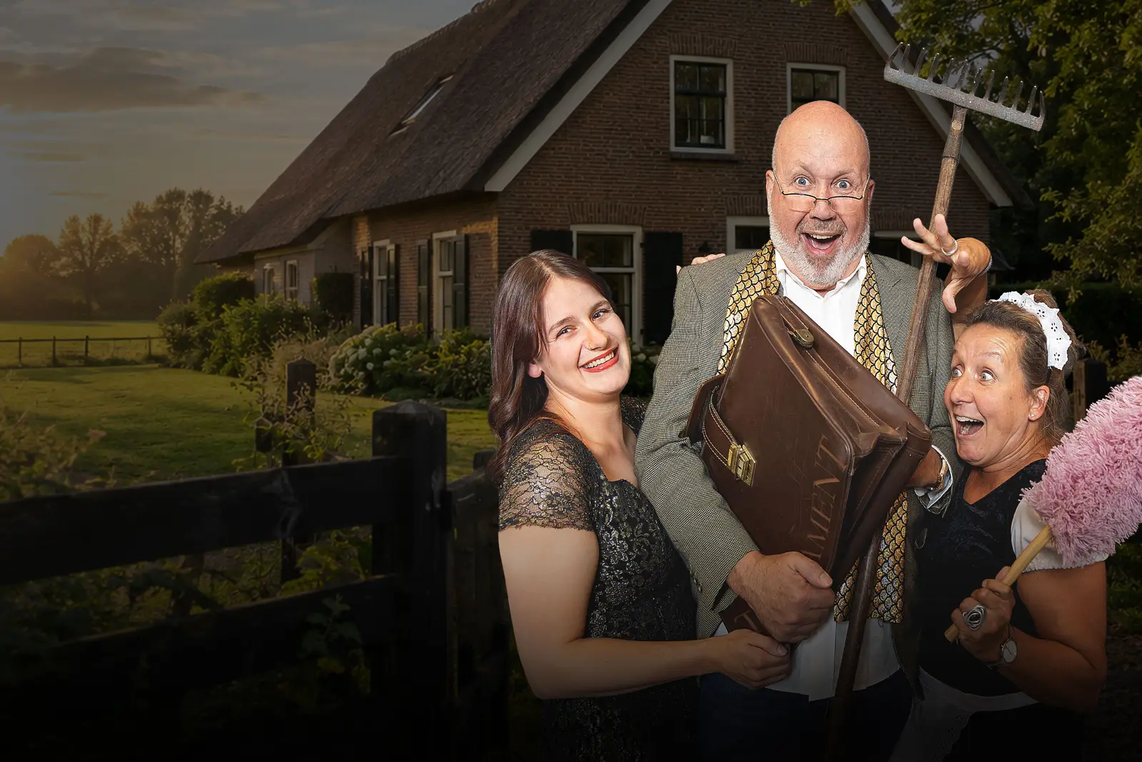 Drie spelers van Wat ’n Spul voor een boerderij: een man met een hark en een aktetas, een vrouw met een plumeau en een jonge vrouw in een zwarte jurk lachen in de camera.